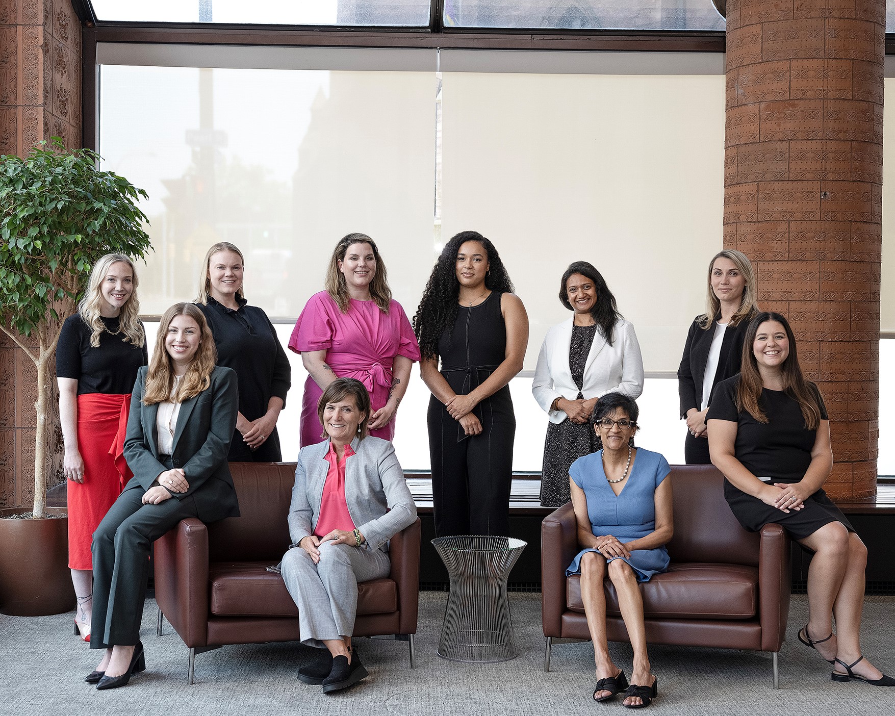 Ten women seated and standing in an office setting